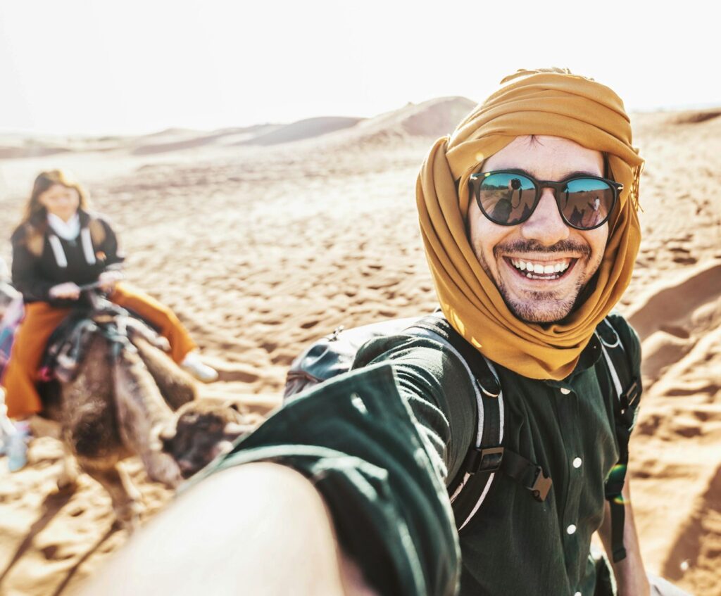 Happy tourist having fun enjoying group camel ride tour in the desert